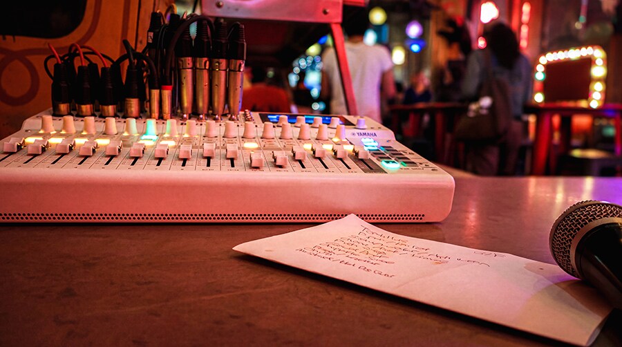 Yamaha MGX16V mixer positioned at front of house with microphone and performance playlist visible.