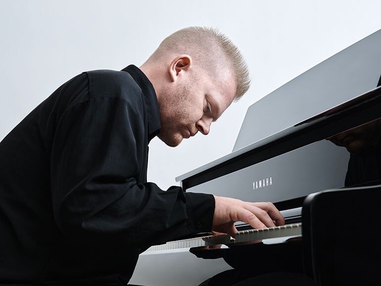 A person immersed in the performance of Yamaha Clavinova CLP-875PE