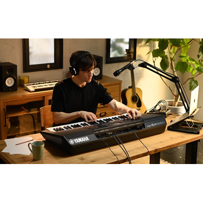 Photo of a person playing the Yamaha Arranger Workstation PSR-SX920 in a room with headphones on.