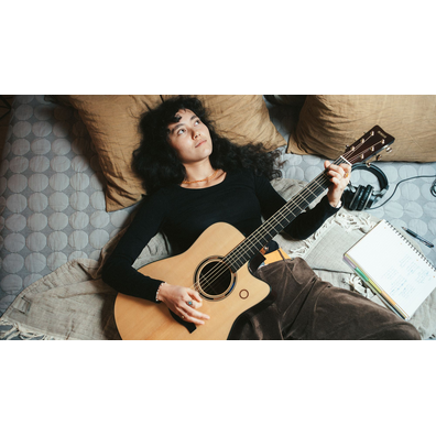 Person lying on a bed playing the TAG3 C acoustic guitar.