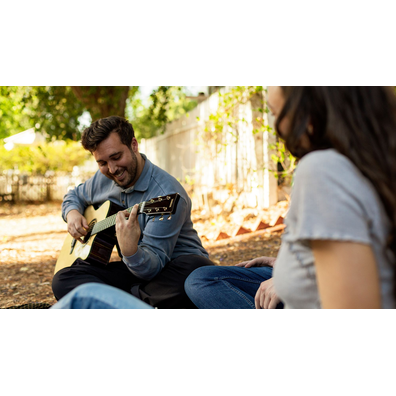 Man smiling while playing the TAS3 C acoustic guitar outdoors.