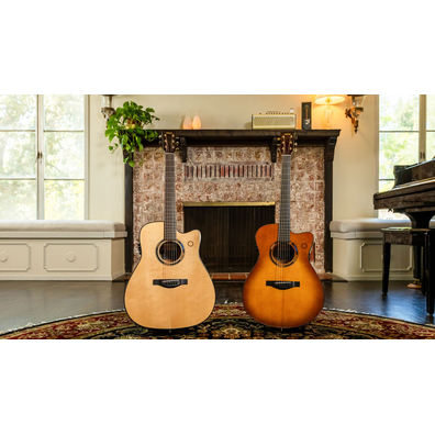 Two acoustic guitars standing in front of a fireplace indoors.